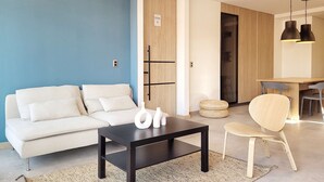 A modern living room with a white sofa, a black coffee table, and a dining area with a wooden table and chairs. - w Elegant 2BR w Amazing Deco in Medellin (Medellín)