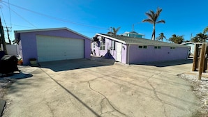 A two-story house with a garage, a small porch, and a driveway. - Lil Lavender Whole House (Fort Myers Beach)