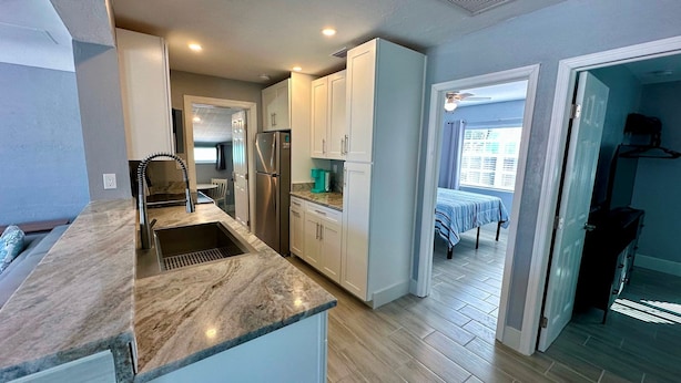 A modern kitchen with a marble countertop, stainless steel appliances, and a dining area with a table and chairs. - Lil Lavender Whole House (Fort Myers Beach)