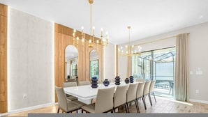 A modern dining room with a large table, multiple chairs, a chandelier, and large windows. - Paradiso 12bd Pool Summerkitchen Gameroom Cinema (Orlando)