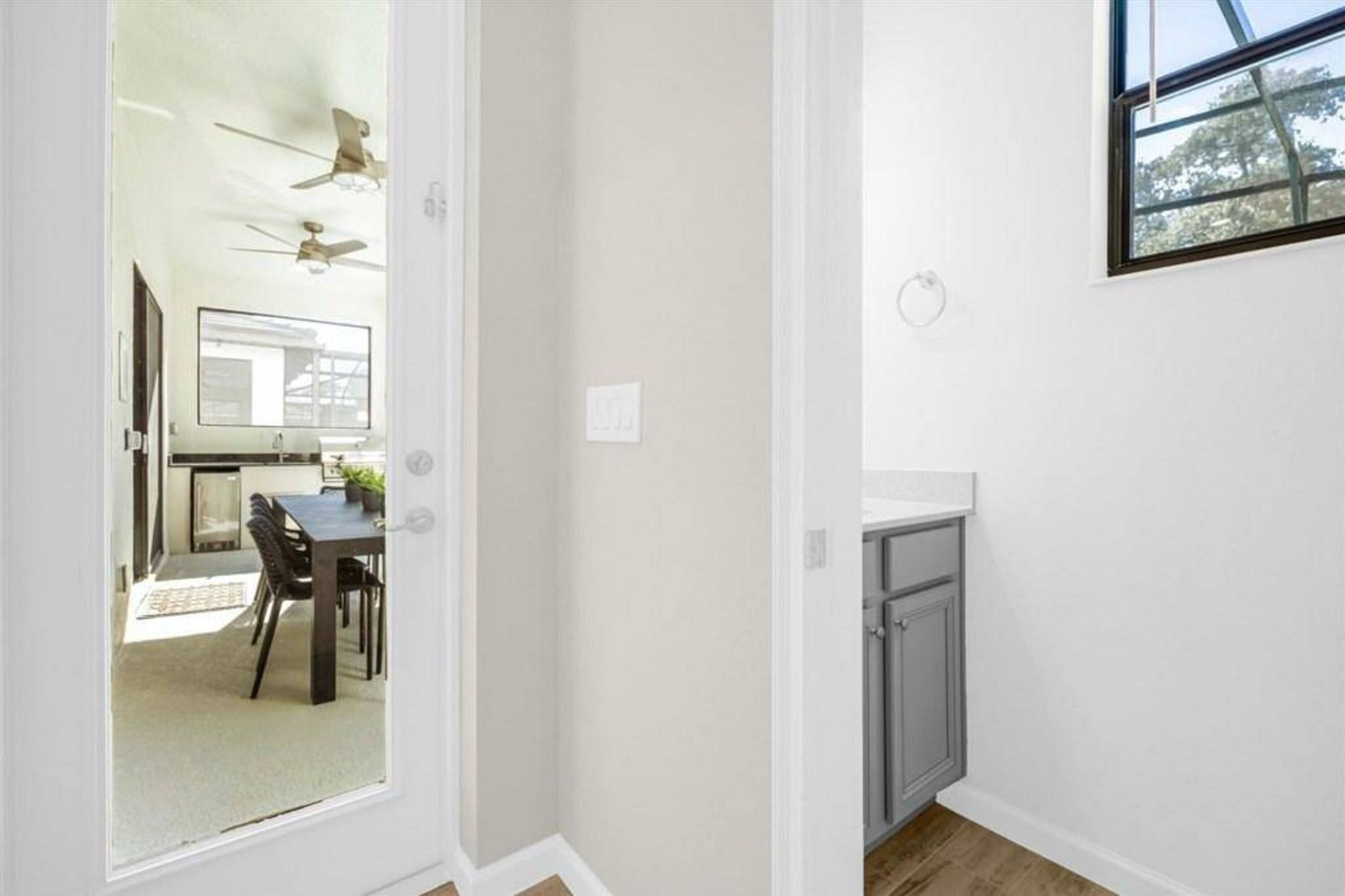 Un couloir comprenant un coin repas, un ventilateur de plafond et une fenêtre donnant sur des arbres.