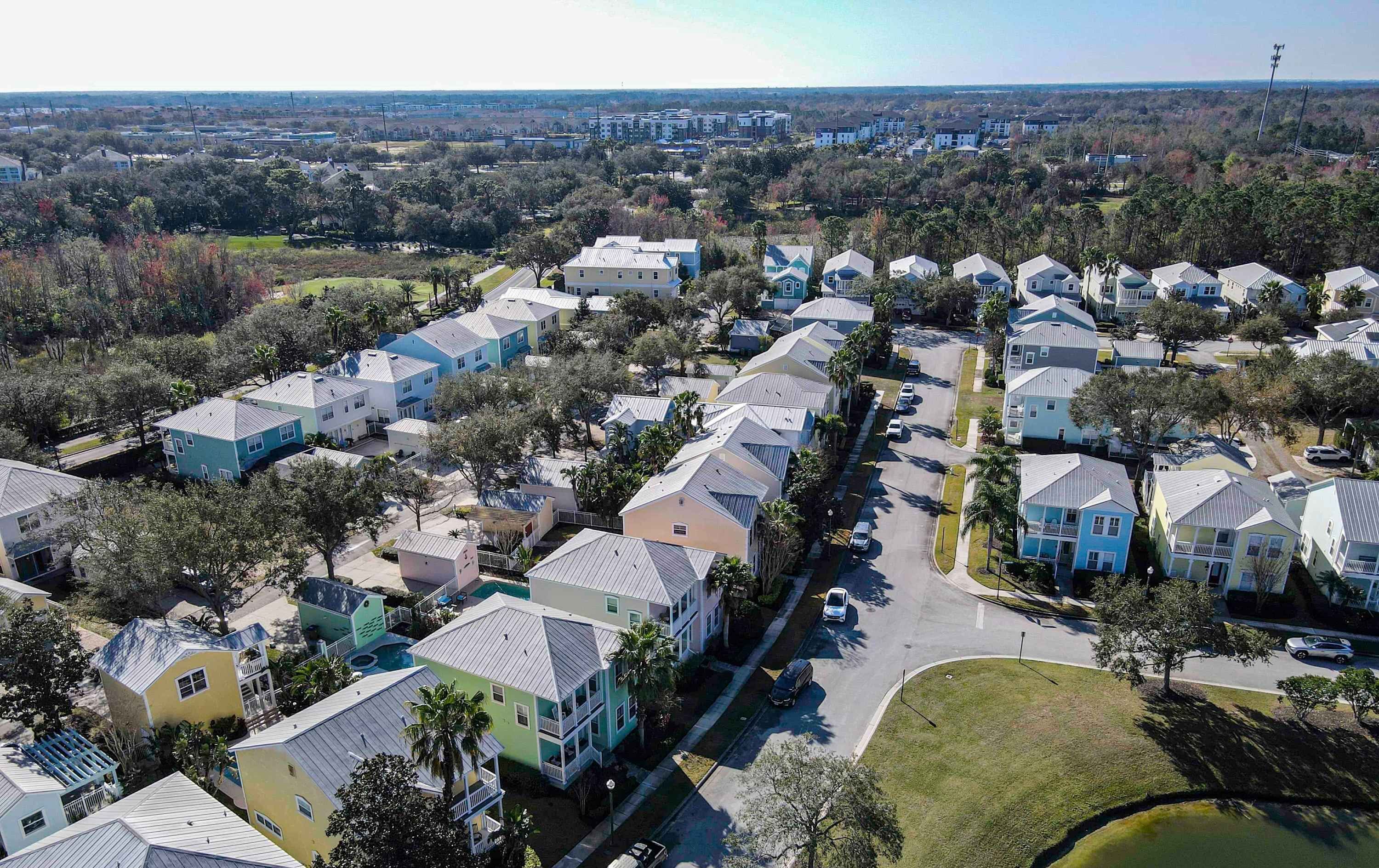 An aerial view of a residential area with multiple two-story houses, roads, and surrounding greenery.