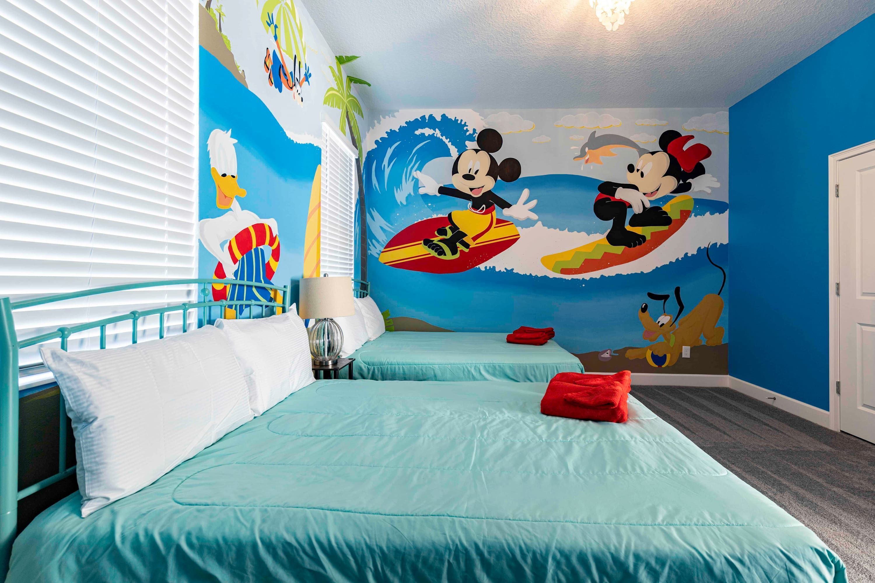 A hotel room with two beds, a beach-themed mural, and a window with blinds.