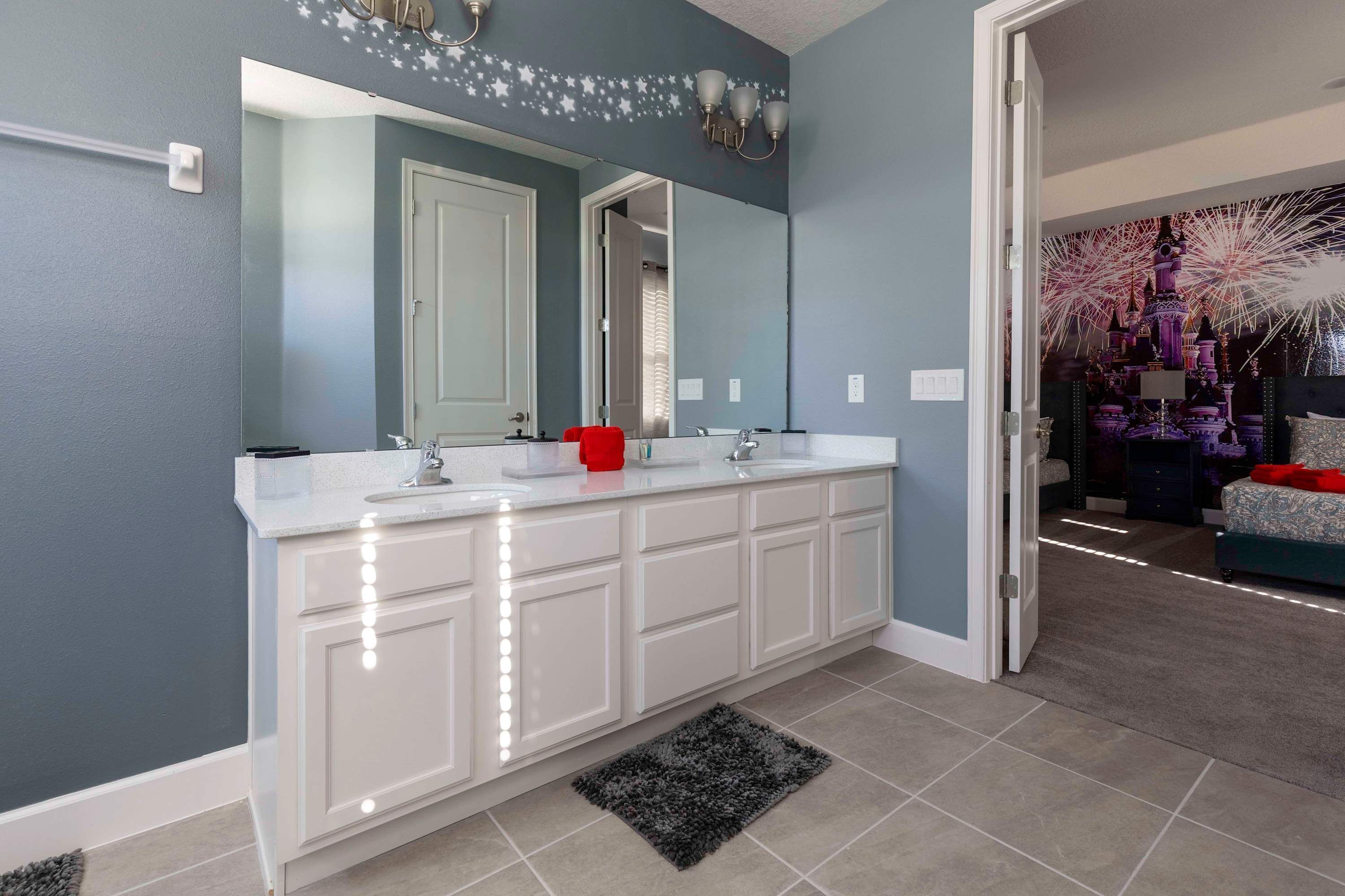 Un baño moderno con lavamanos doble, un espejo grande y una lámpara decorativa en la pared.