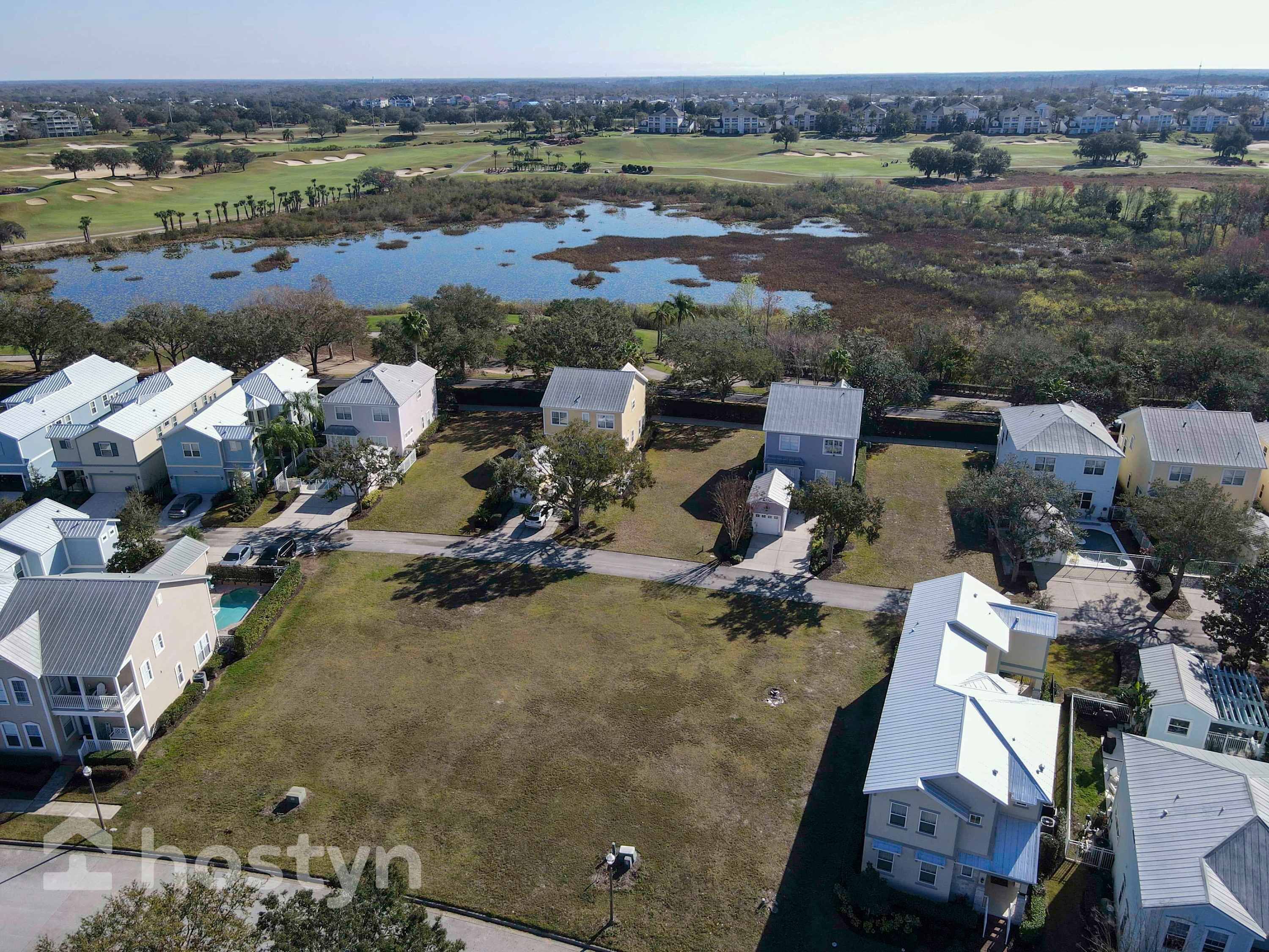 A residential area with houses, a golf course, and a body of water.