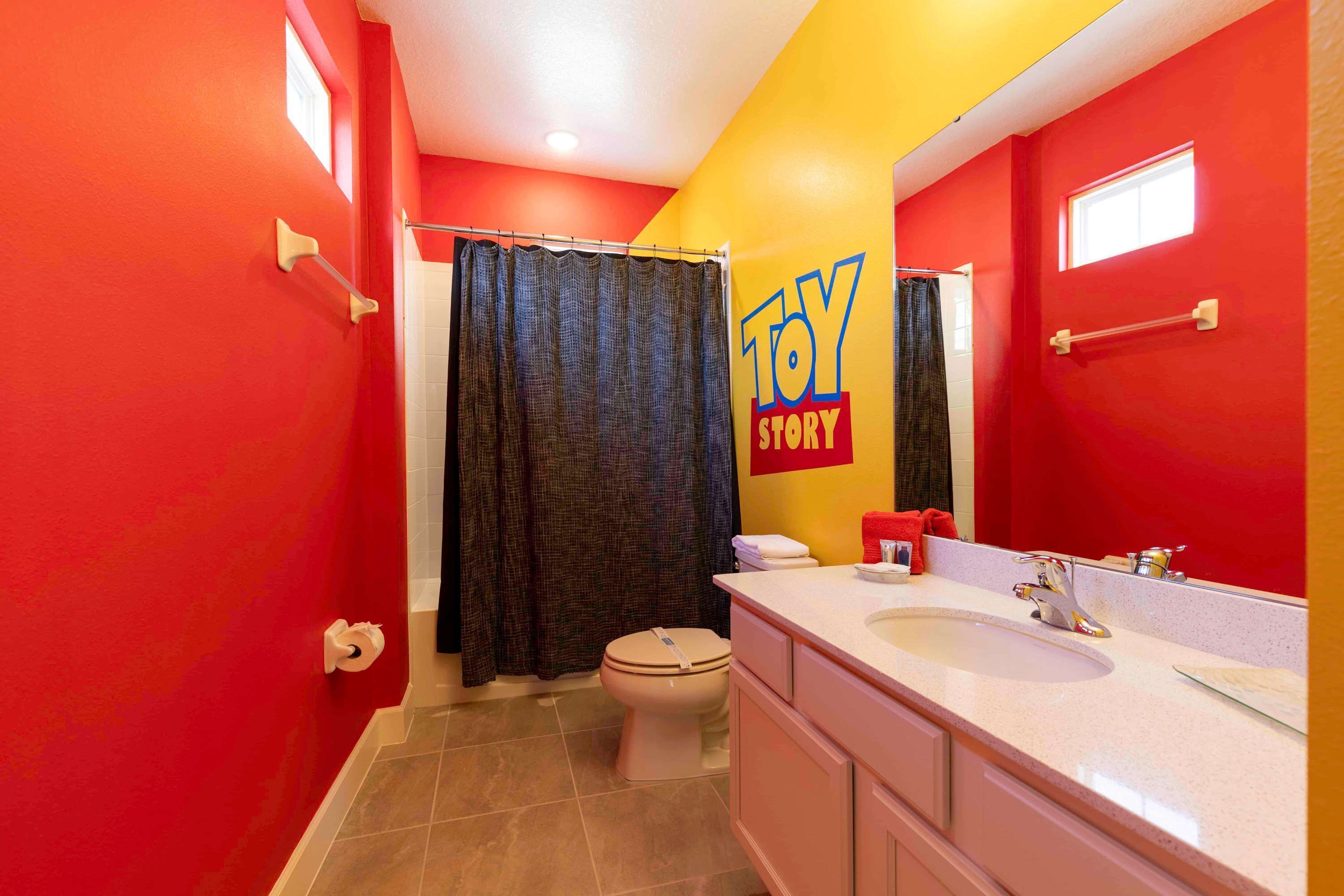 A bathroom with red walls, a white toilet, a shower curtain, and a sink with a mirror.