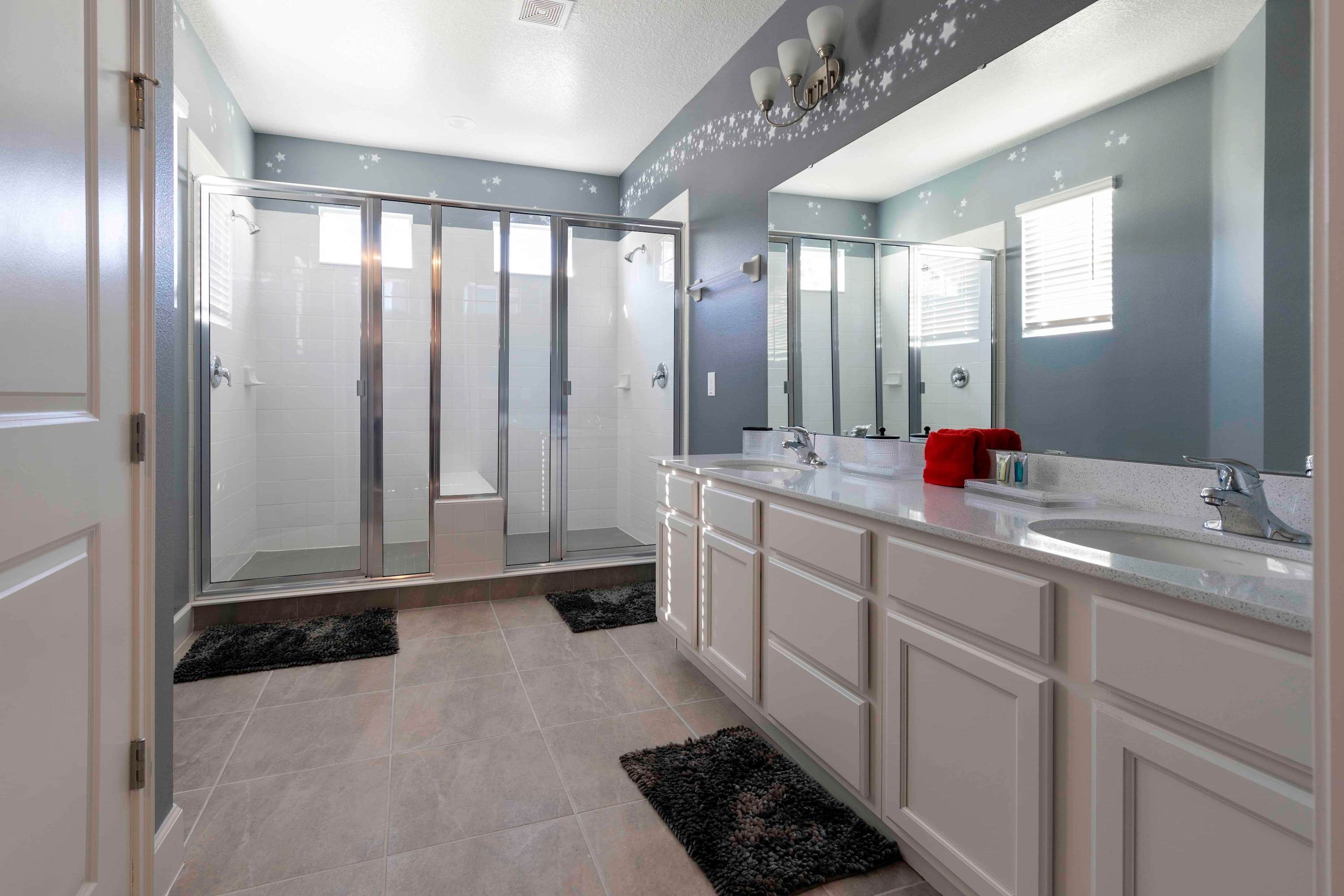 Un baño moderno con cabina de ducha, lavamanos doble y un espejo grande.