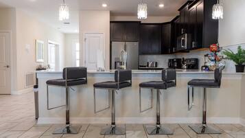 A modern kitchen with dark cabinets, stainless steel appliances, and a central island with bar stools.