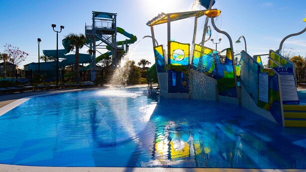 A water park with a large pool, water slides, and a water feature spraying water. - Luxury 9BR Villa Poolside Bliss n Pool Table Fun (Kissimmee)