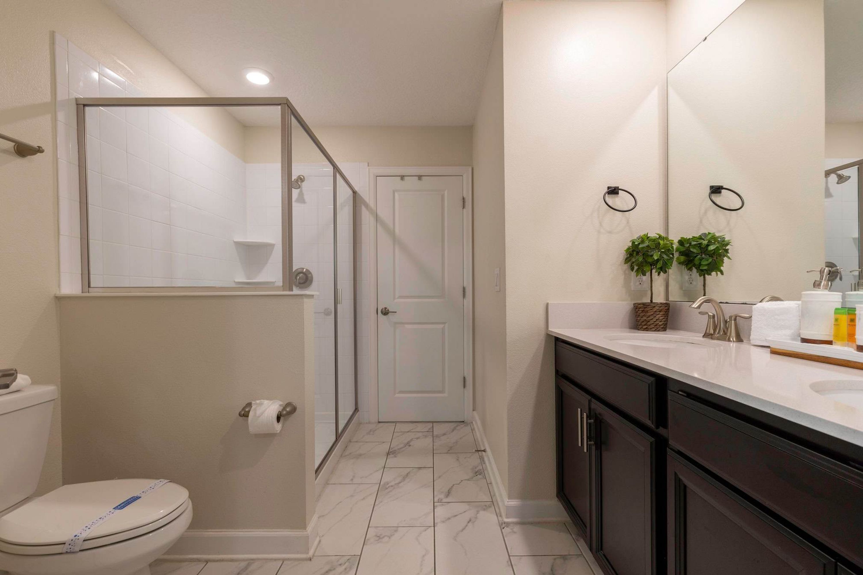 A modern bathroom with a toilet, shower, and sink.