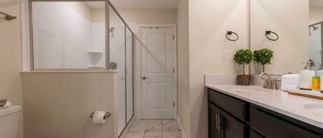 A modern bathroom with a toilet, shower, and sink.