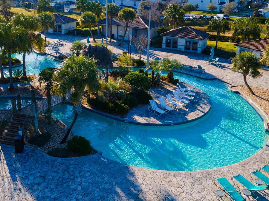 A resort with a large swimming pool, palm trees, and lounge chairs.