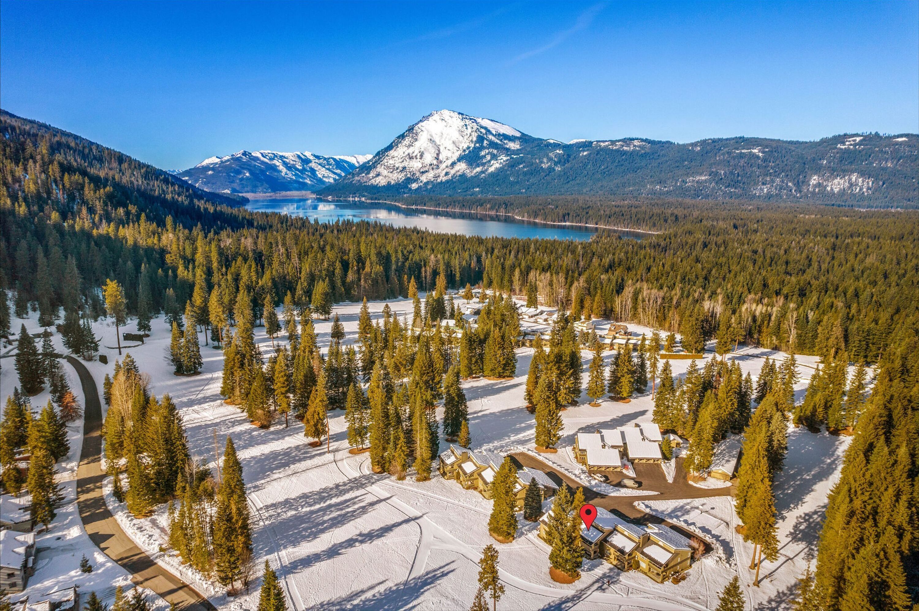 An aerial view of a resort with cabins, a lake, and mountains in the background.