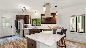 Una cocina moderna con una isla grande, electrodomésticos de acero inoxidable y armarios de madera.