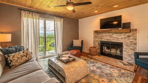 A living room with a sofa, a coffee table, a fireplace, and a television. - Full Kitchen Mountain Views Indoor Pool Access (Gatlinburg)