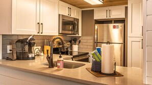 A modern kitchen with white cabinets, stainless steel appliances, and a wooden ceiling. - Full Kitchen Mountain Views Indoor Pool Access (Gatlinburg)