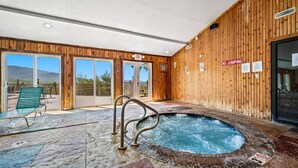 Un espace avec un bain à remous, doté d’un mur en bois, d’un panneau indiquant la sortie et d’un panneau interdisant de sauter.