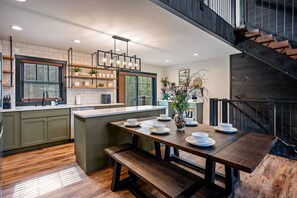 Una cocina moderna con una isla central, suelo de madera y una escalera que lleva a un nivel superior.