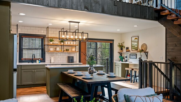 Una cocina moderna con una isla central, piso de madera y una escalera que sube a un nivel superior.