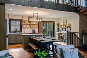 Una cucina moderna con isola centrale, pavimento in legno e una scala che conduce a un piano superiore.