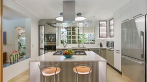 Una cocina moderna con una isla central, electrodomésticos de acero inoxidable y vistas al exterior.