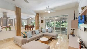 Amplia sala de estar con un sofá modular grande, una mesa de centro y un comedor con sillas.