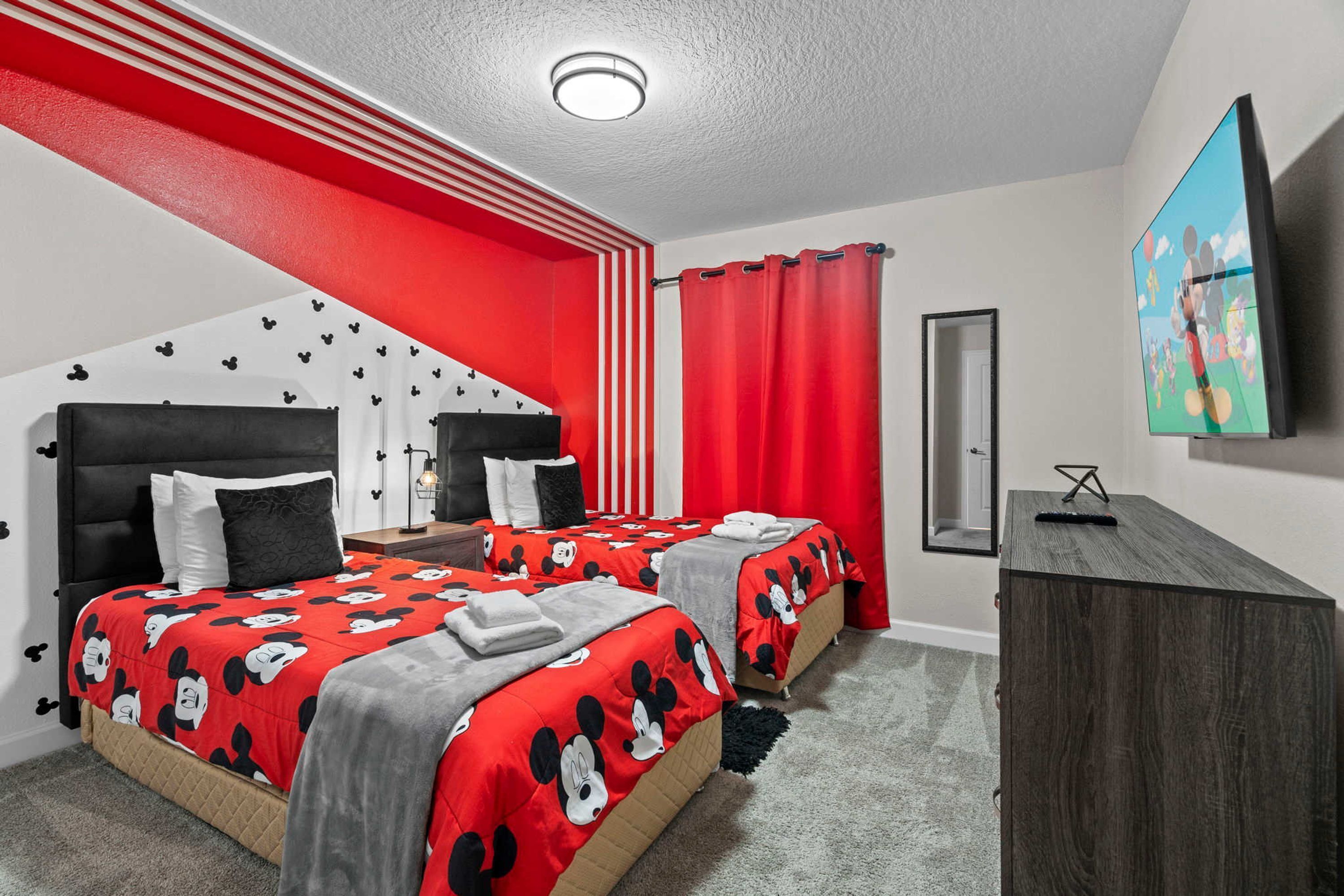 Habitación de hotel con dos camas, televisión y escritorio.