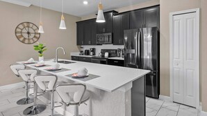 A modern kitchen with a central island, stainless steel appliances, and bar stools.