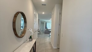 A hallway with a marble console table, a round mirror, and a staircase leading to an upper floor.