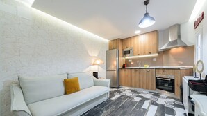 A modern kitchen with wooden cabinets, stainless steel appliances, and a black and white patterned floor. - GuestReady - A lovely home near Plaza Mayor (Madrid)