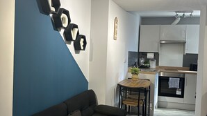 A modern living room with a dark sofa, a blue accent wall, and a kitchen in the background. - Cozy Studio In The City Centre by Luxesuites (Sheffield)