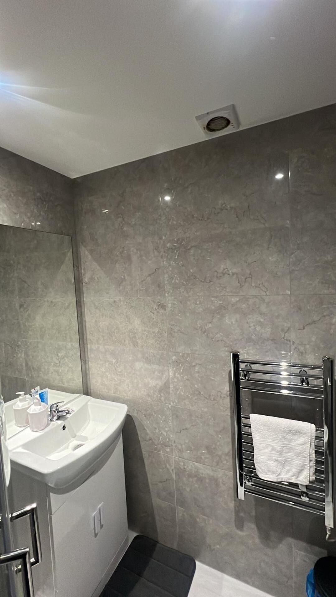 Une salle de bain avec un lavabo, un miroir et un porte-serviettes.