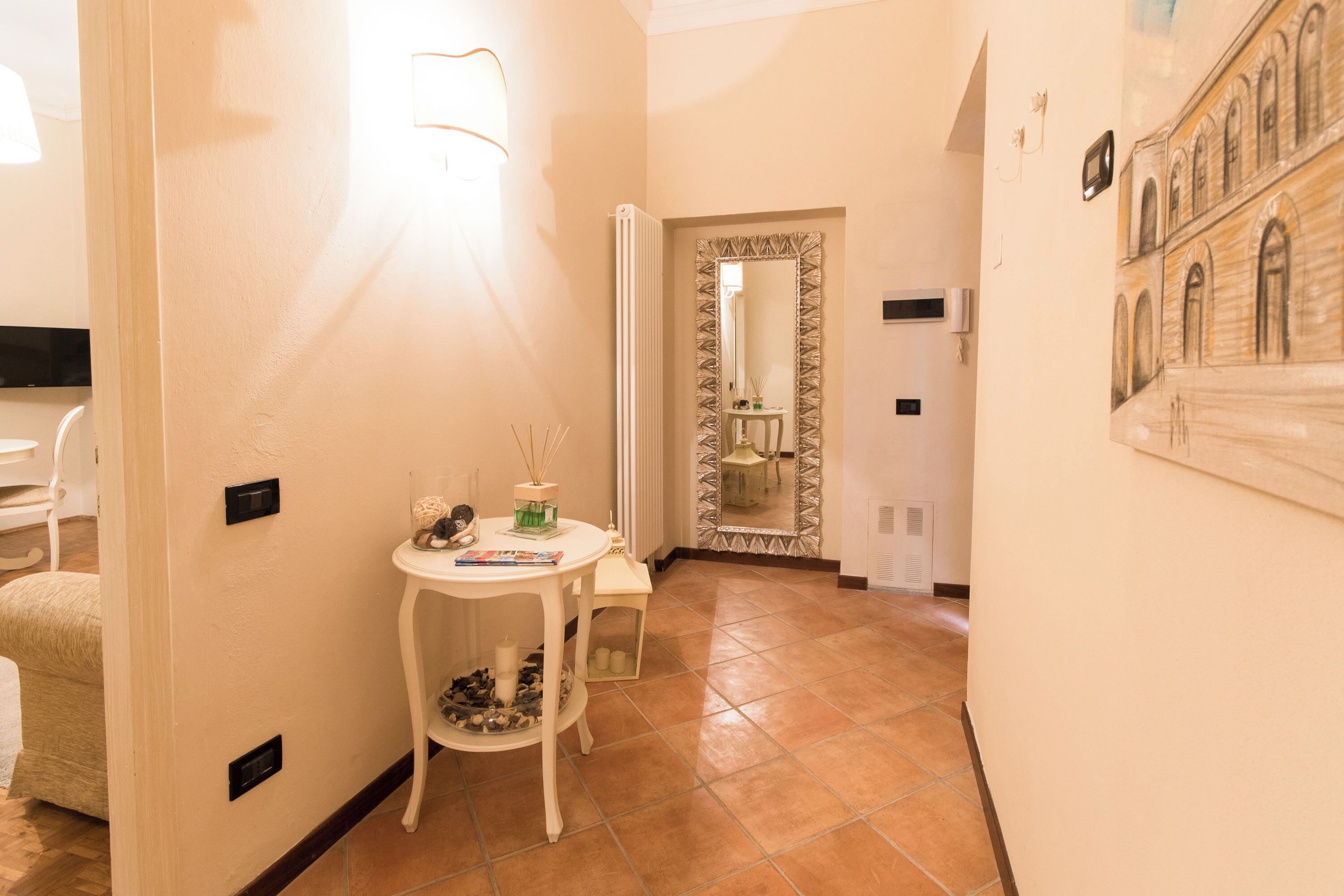 A hallway with a white table, a mirror, and a tiled floor.
