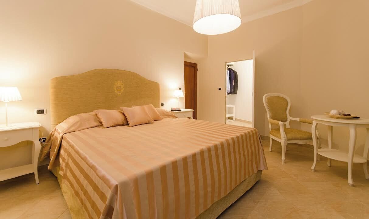 A hotel room with a bed, bedside tables, a chair, and a small table.