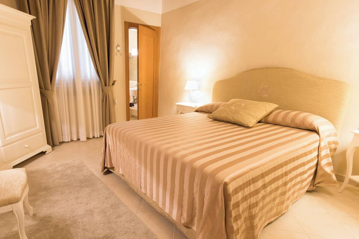 Een slaapkamer met een groot bed, een nachtkastje, een stoel en een garderobe.