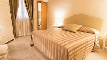 A bedroom with a large bed, a nightstand, a chair, and a wardrobe.