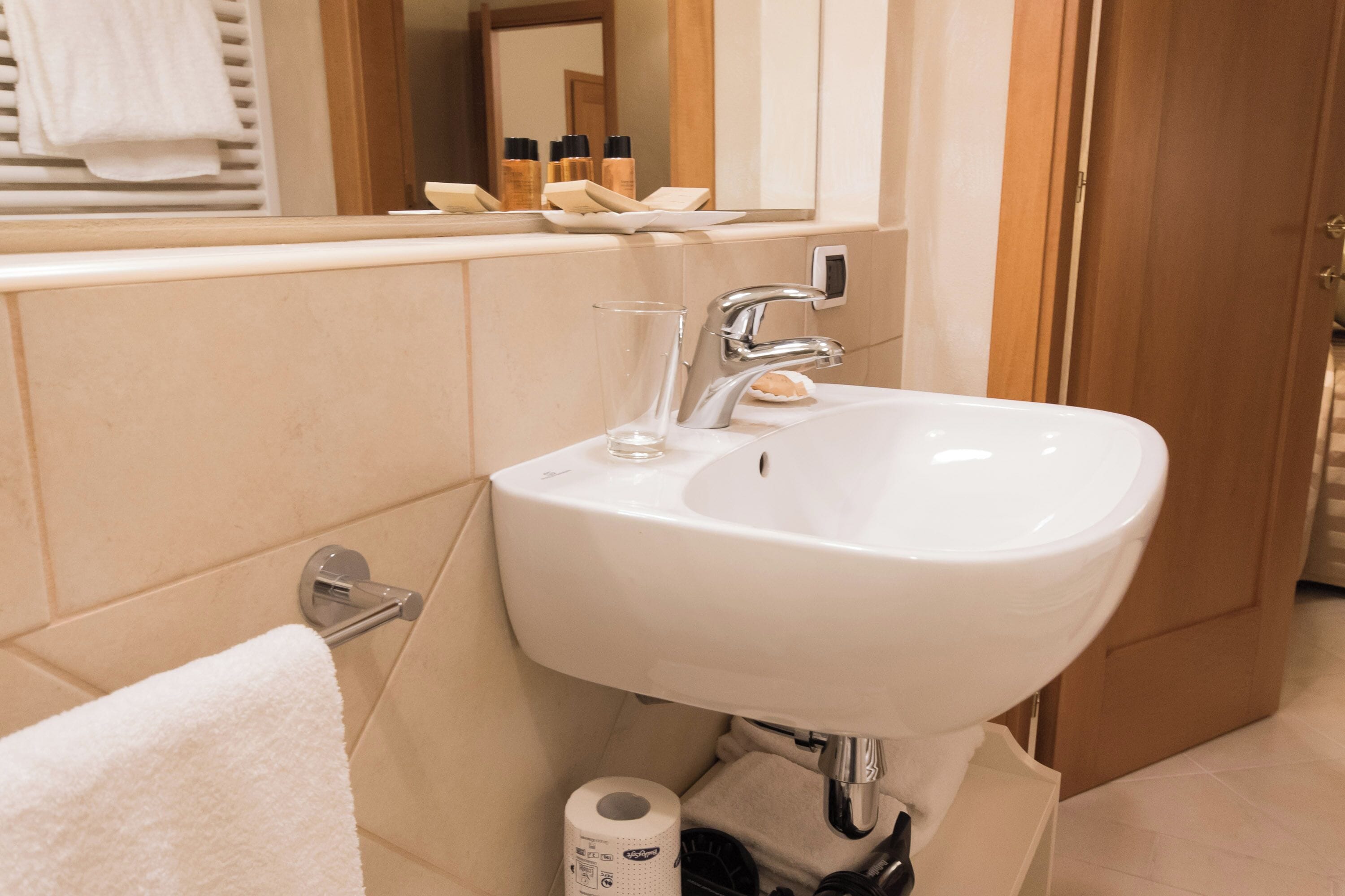 A bathroom with a white sink, a mirror, and toiletries on the counter.