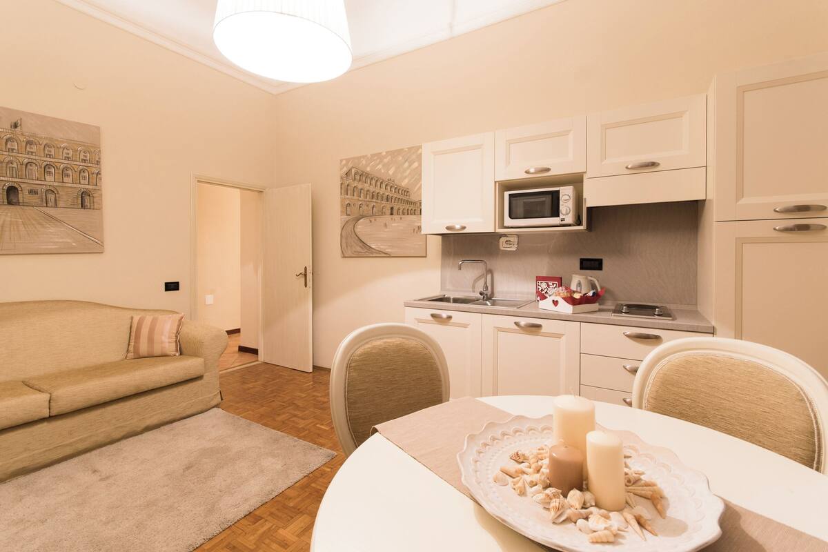 Een knus woongedeelte met kitchenette, een eettafel met kaarsen en een bank.