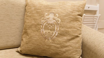 En beige soffa med en dekorativ kudde som har ett präglat emblem.