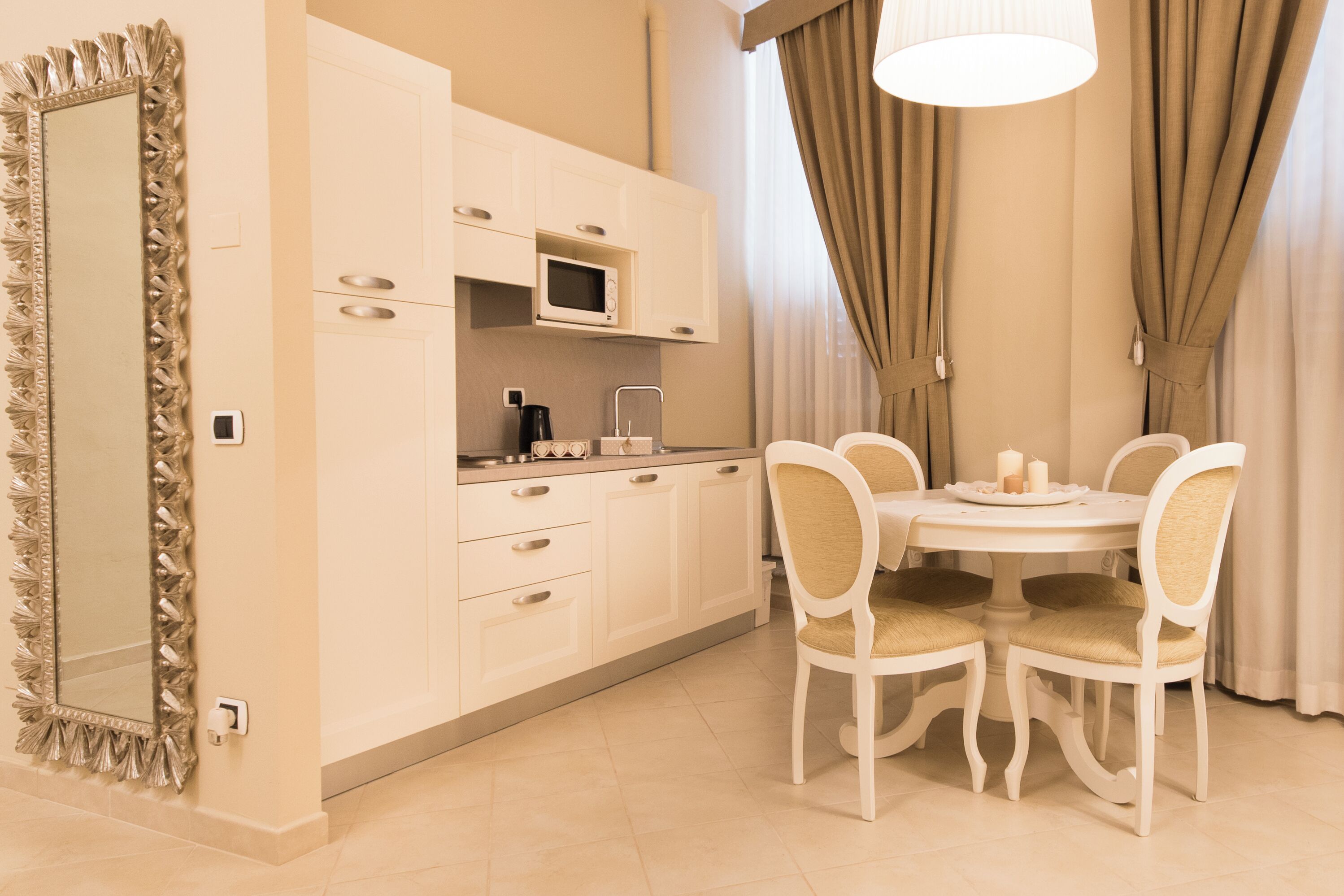 A modern kitchen with white cabinets, a microwave, and a dining table with four chairs.
