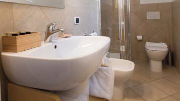 A modern bathroom with a large white sink, a toilet, and a glass-enclosed shower.