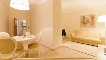 Une chambre d’hôtel comprenant un coin repas, un canapé, un tableau et une lampe.