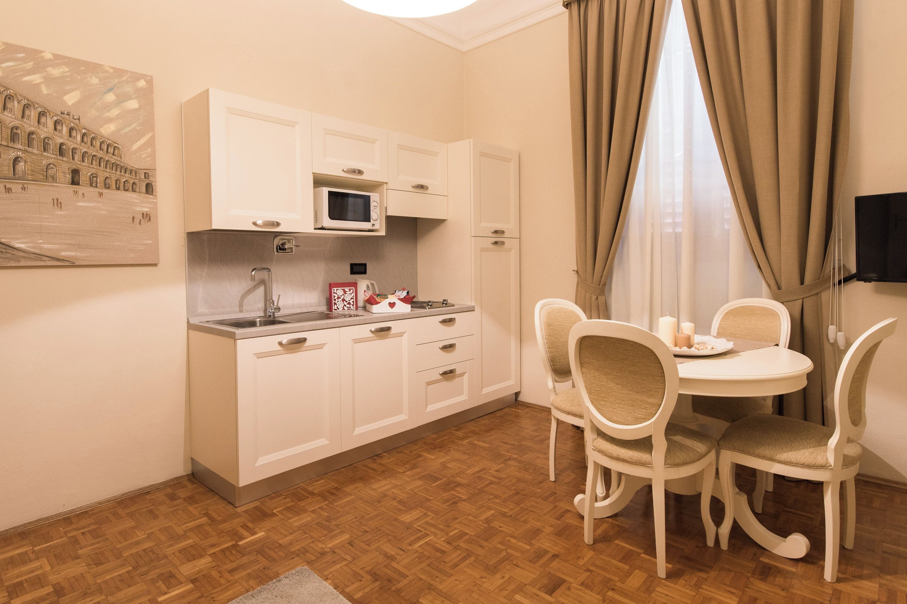 A compact kitchen with white cabinets, a microwave, and a dining area with a table and chairs.