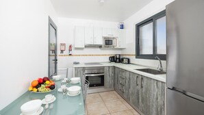 Eine moderne Küche mit weißen Schränken, einem Edelstahl-Kühlschrank, einer Mikrowelle und einer Kaffeemaschine.