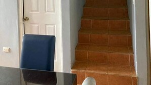 A staircase with a handrail leading to a landing, a white door, and a blue chair.