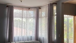 A living room with a grey sectional sofa, a ceiling light fixture, and a sliding glass door leading to an outdoor area.
