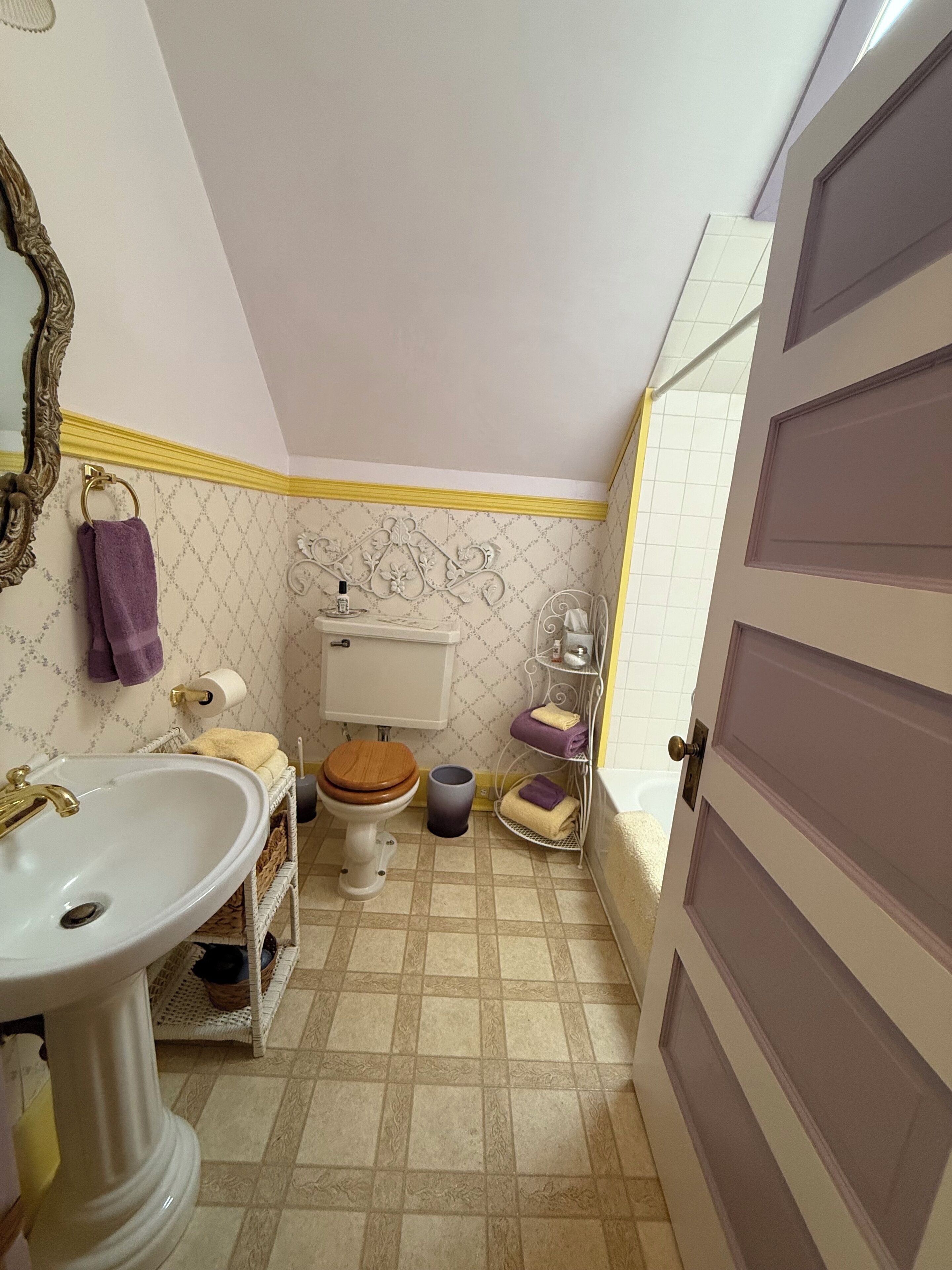 A compact bathroom with a pedestal sink, toilet, and a small shelf with towels.