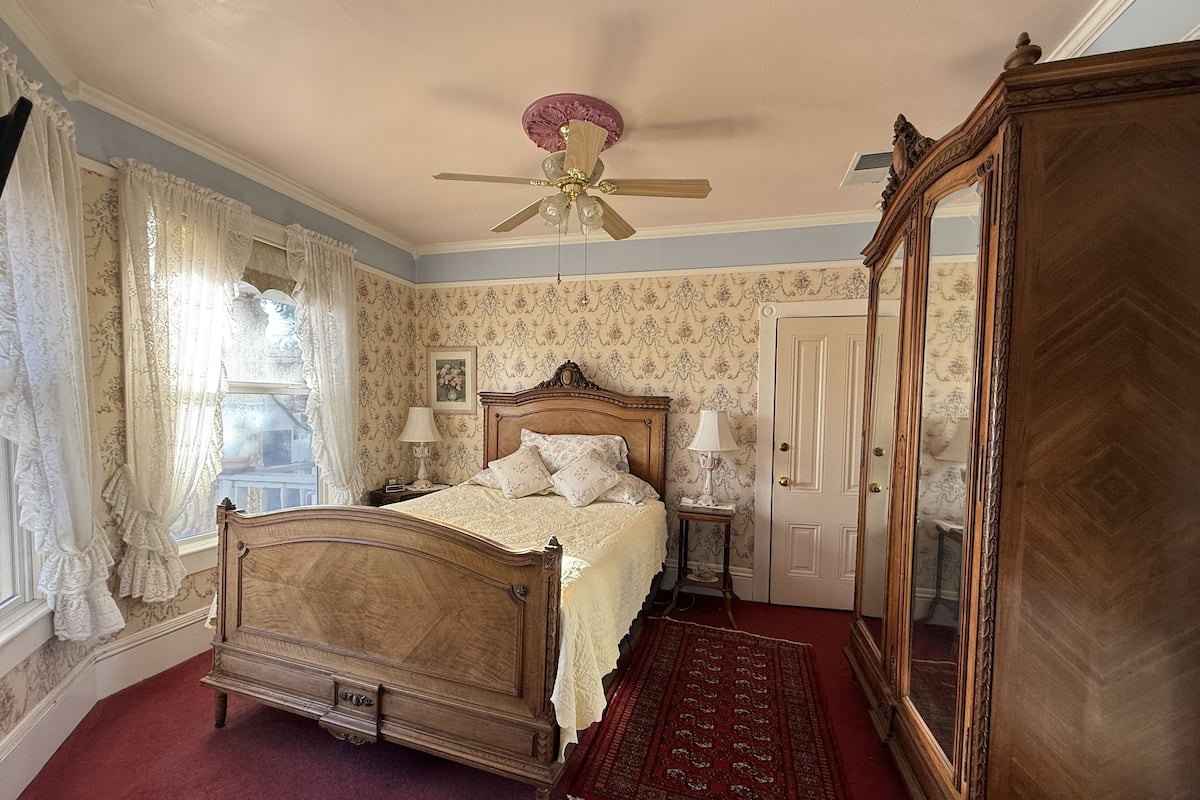 Ein klassisches Schlafzimmer mit Himmelbett, Deckenventilator und großem Spiegel.