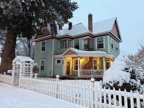 Ein zweistöckiges Haus mit Veranda, Schornstein und weißem Zierzaun.