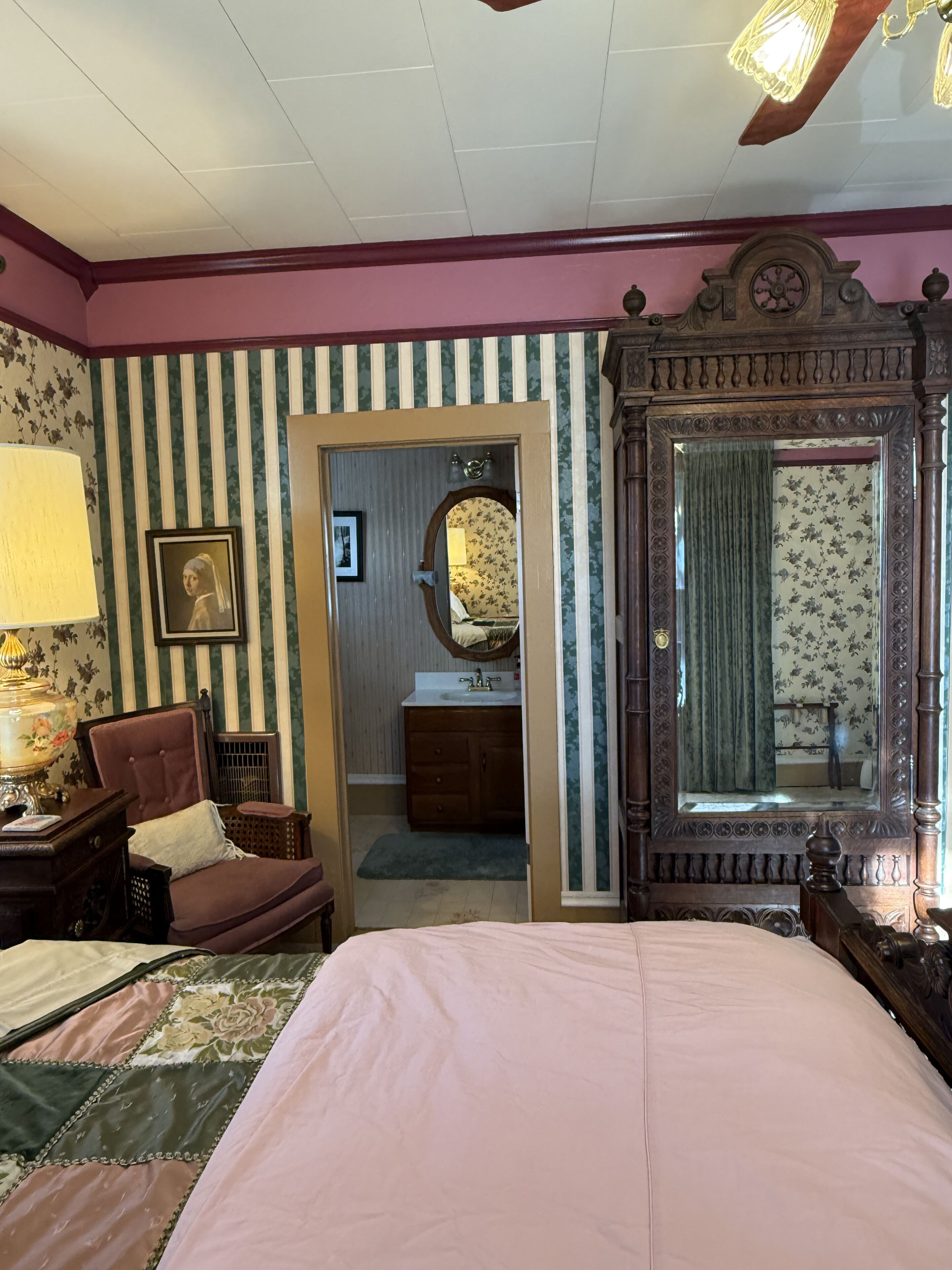 Une chambre à coucher avec un lit, une chaise, un bureau et un miroir.